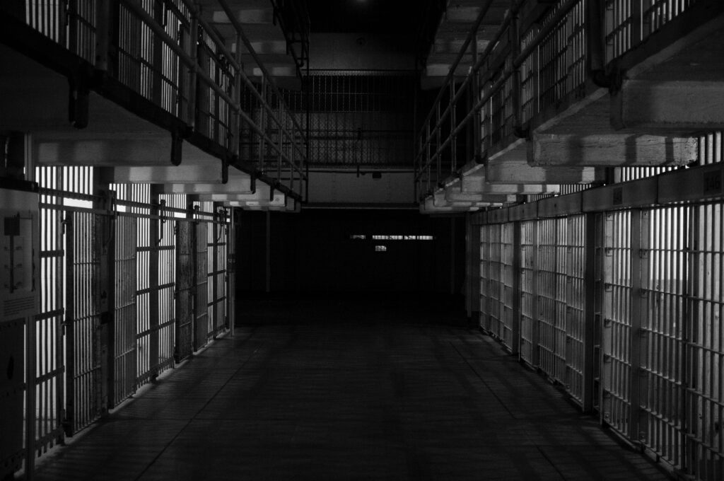 Black and white image of the inside of  a jail with cells.